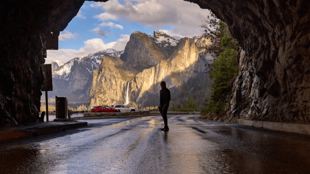 view of mountains looking out of a tunnel, person in the middle.